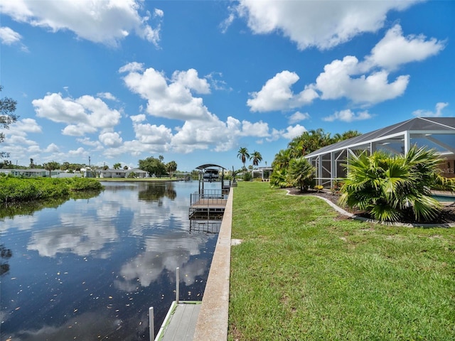 view of dock with a water view, glass enclosure, and a lawn