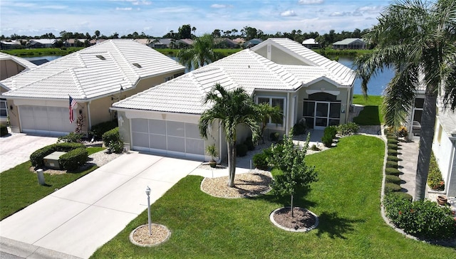 ranch-style home with a garage, a water view, and a front lawn