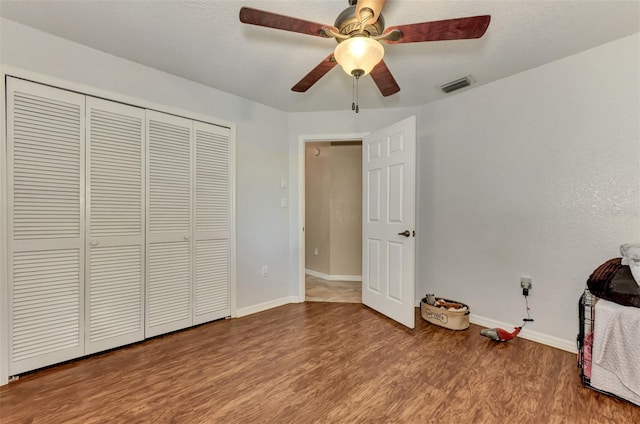 unfurnished bedroom featuring hardwood / wood-style flooring, a closet, and ceiling fan