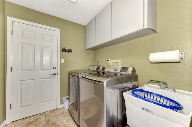 laundry room featuring light tile patterned floors, separate washer and dryer, sink, and cabinets