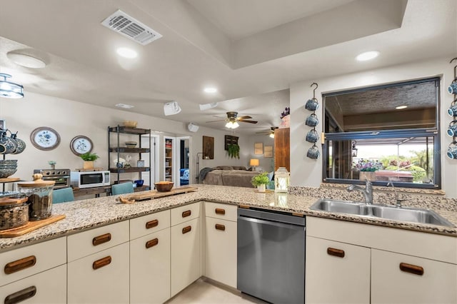 kitchen with light stone counters, sink, kitchen peninsula, and black dishwasher