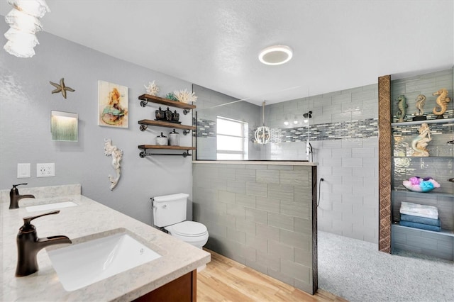 bathroom with vanity, wood-type flooring, toilet, and tiled shower