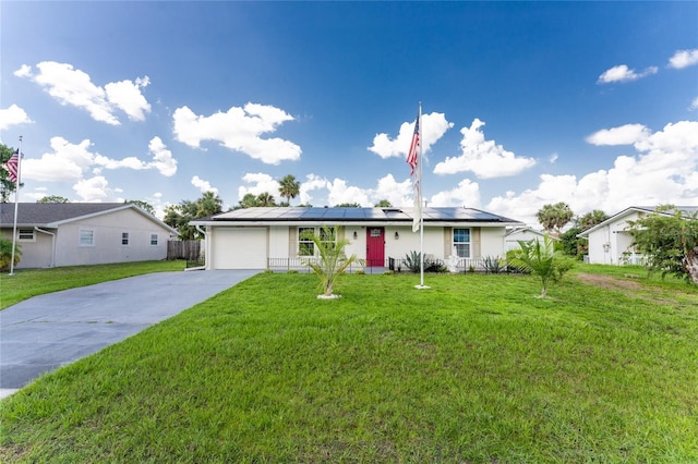 ranch-style home with a garage, a front yard, and solar panels