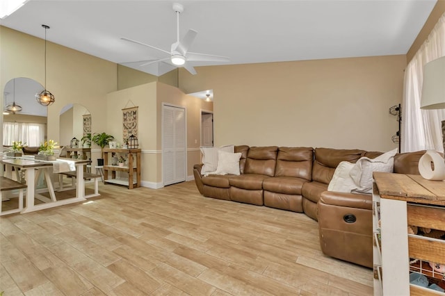 living room with ceiling fan, light hardwood / wood-style flooring, and lofted ceiling