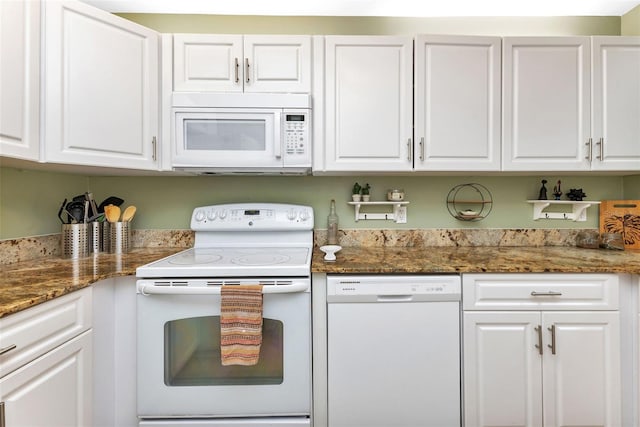 kitchen featuring white cabinets, dark stone countertops, and white appliances