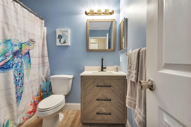 bathroom with hardwood / wood-style floors, vanity, toilet, and walk in shower