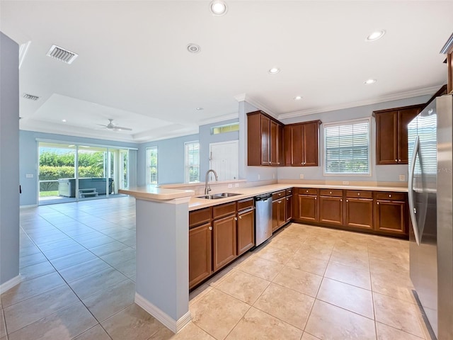 kitchen featuring ceiling fan, sink, stainless steel appliances, a raised ceiling, and kitchen peninsula