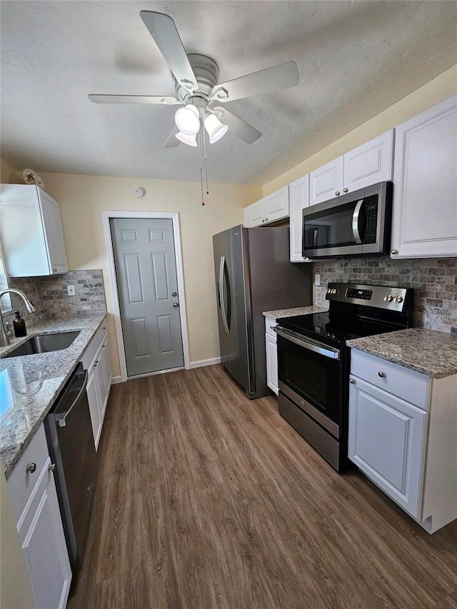 kitchen with decorative backsplash, appliances with stainless steel finishes, light stone counters, sink, and white cabinetry