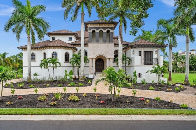 mediterranean / spanish house featuring stucco siding and a tiled roof