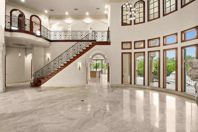 unfurnished living room with crown molding, stairs, an inviting chandelier, arched walkways, and marble finish floor