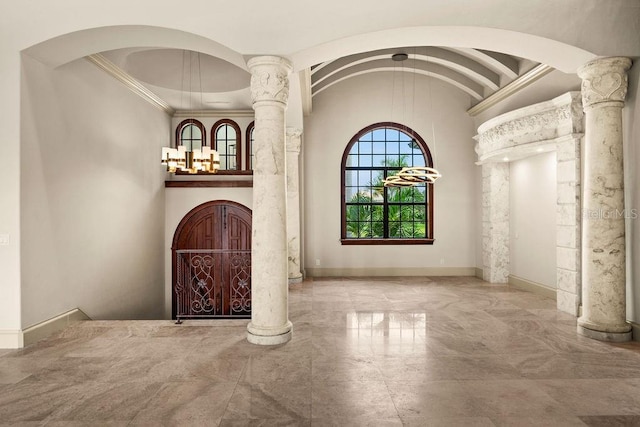 foyer entrance featuring crown molding, baseboards, and ornate columns