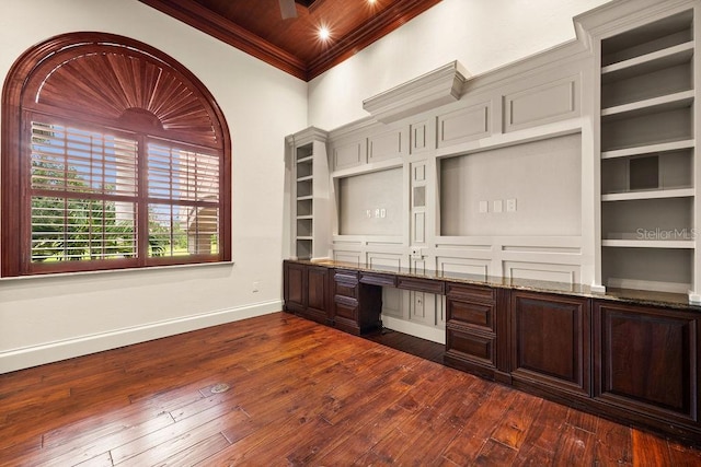 unfurnished office featuring ornamental molding, baseboards, dark wood-style flooring, and built in study area