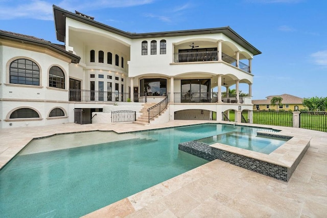 back of property featuring a balcony, ceiling fan, a swimming pool with hot tub, and a patio area