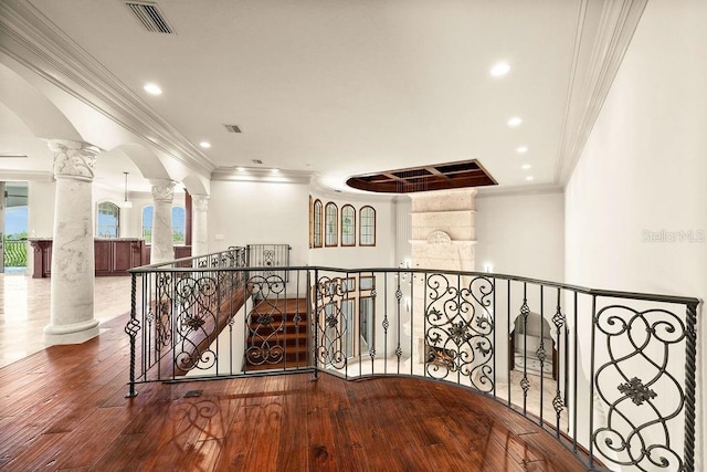 hall with decorative columns, ornamental molding, and hardwood / wood-style floors