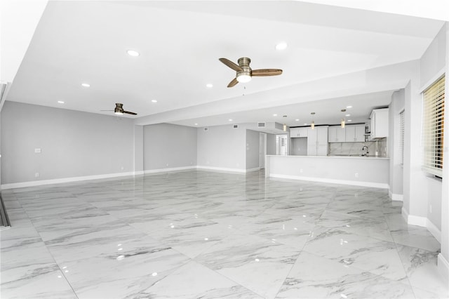 unfurnished living room featuring ceiling fan and sink