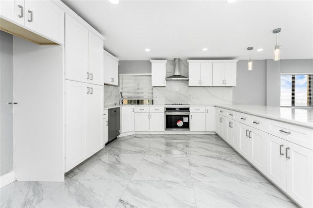 kitchen featuring decorative backsplash, stainless steel oven, wall chimney range hood, white cabinetry, and hanging light fixtures