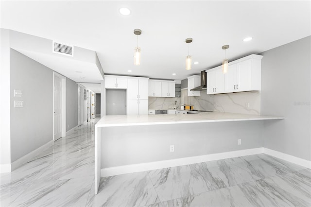 kitchen featuring wall chimney exhaust hood, kitchen peninsula, white cabinets, and decorative light fixtures