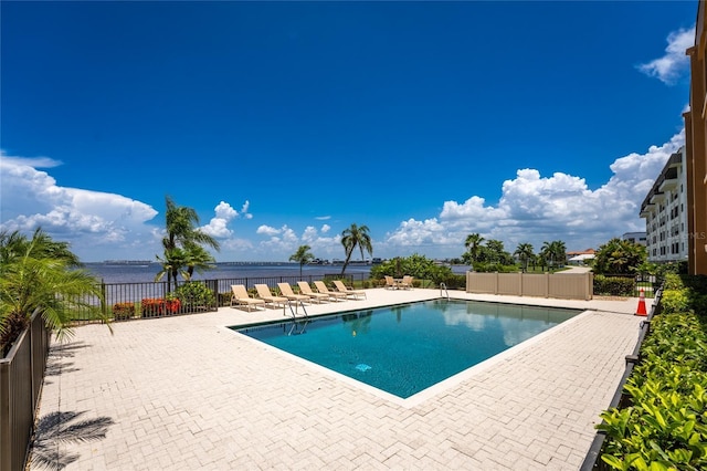 view of pool with a water view and a patio