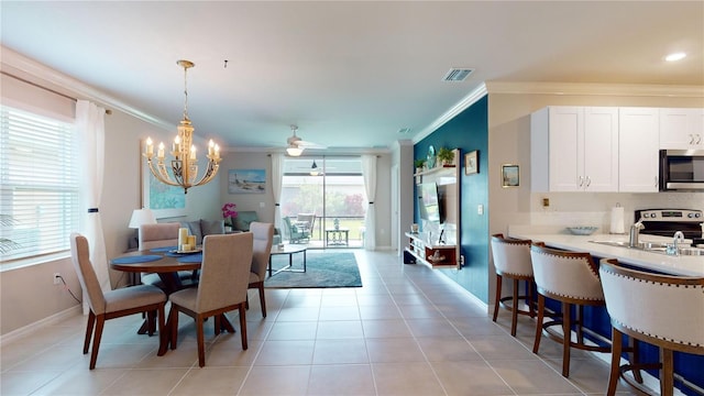 tiled dining room with ceiling fan with notable chandelier, ornamental molding, sink, and plenty of natural light