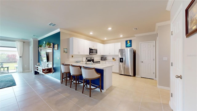 kitchen featuring a kitchen bar, appliances with stainless steel finishes, kitchen peninsula, light tile patterned floors, and white cabinetry