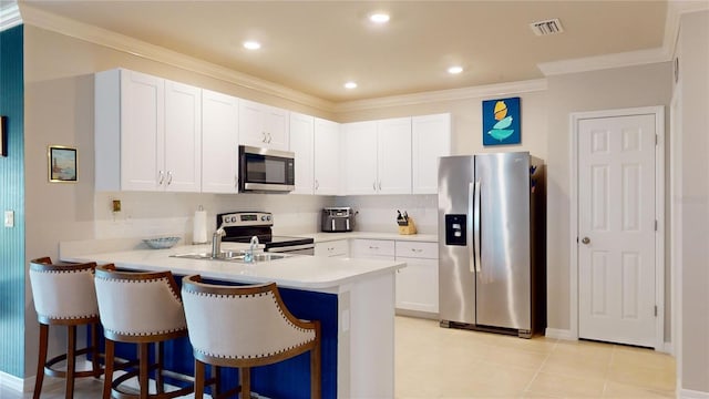 kitchen featuring white cabinetry, stainless steel appliances, crown molding, and tasteful backsplash