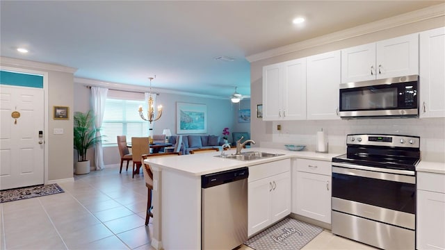 kitchen with a peninsula, a sink, white cabinetry, light countertops, and appliances with stainless steel finishes