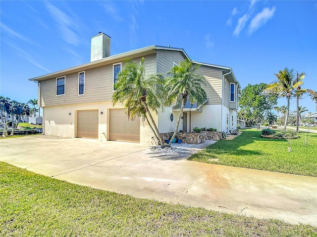 view of front of house with an attached garage, a chimney, a front lawn, and concrete driveway