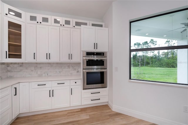 kitchen featuring a wealth of natural light, backsplash, white cabinets, and stainless steel double oven