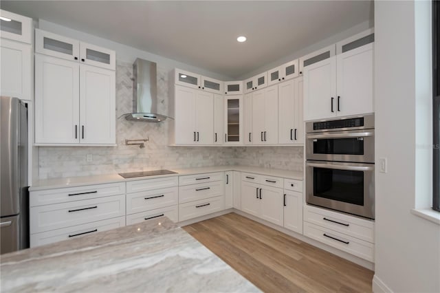 kitchen featuring appliances with stainless steel finishes, wall chimney exhaust hood, and white cabinetry