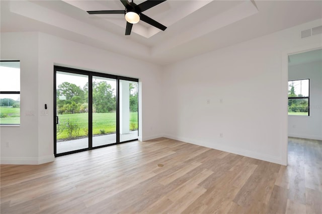 spare room featuring ceiling fan, a tray ceiling, and light hardwood / wood-style floors