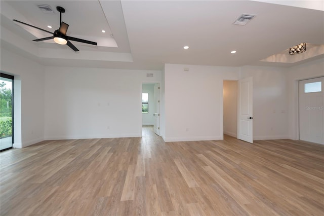 spare room with light hardwood / wood-style floors, a raised ceiling, and ceiling fan