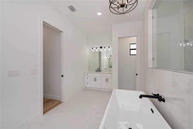 bathroom with tile patterned floors, vanity, a bathing tub, and a notable chandelier