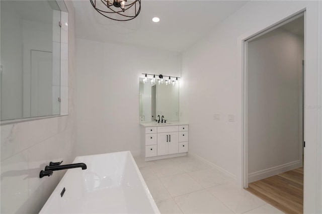 bathroom with a tub to relax in, vanity, and tile patterned floors