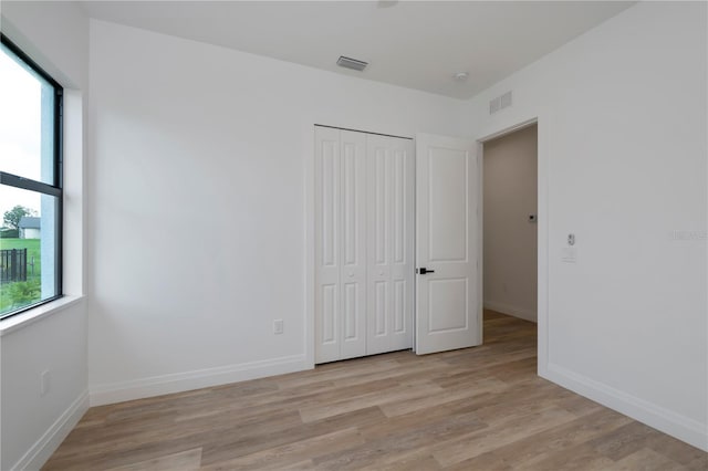 unfurnished bedroom with a closet and light hardwood / wood-style flooring