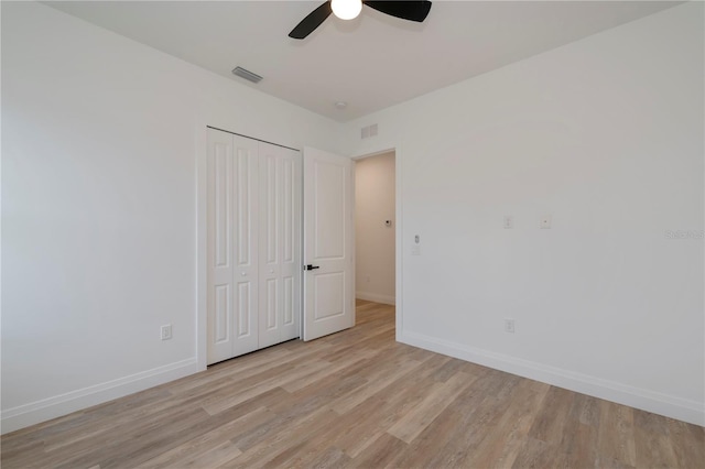 unfurnished bedroom with light wood-type flooring, ceiling fan, and a closet