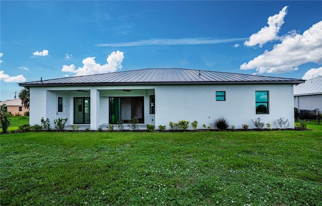 rear view of house featuring ceiling fan and a lawn