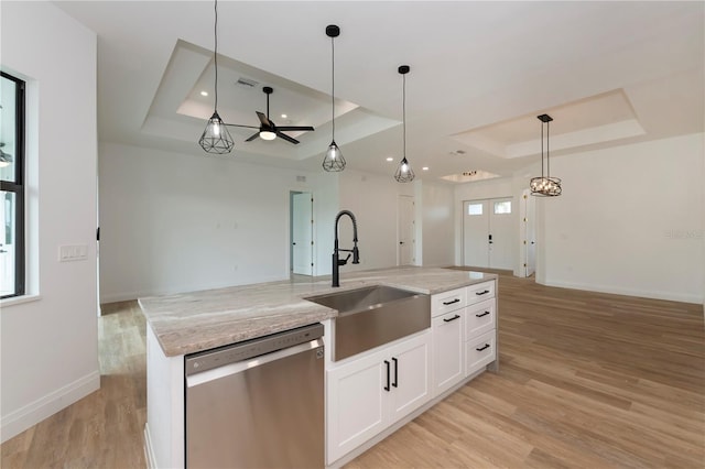 kitchen featuring a tray ceiling, a kitchen island with sink, stainless steel dishwasher, white cabinets, and sink