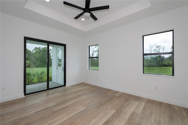 spare room featuring ceiling fan, a tray ceiling, and light hardwood / wood-style flooring