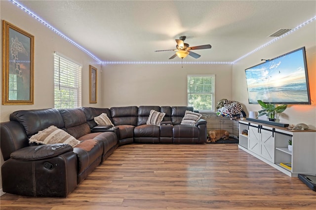 living room featuring wood finished floors, visible vents, a ceiling fan, and ornamental molding
