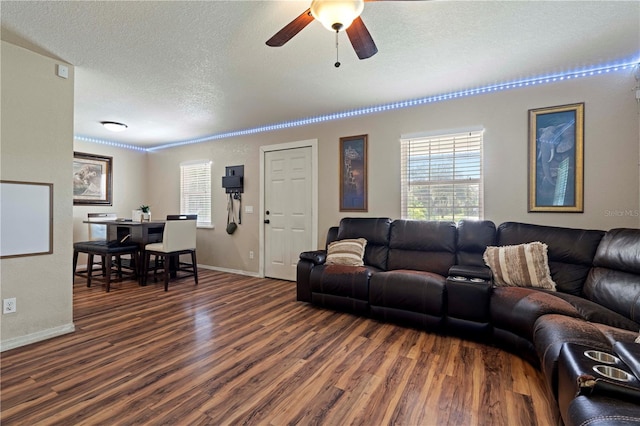 living room featuring ceiling fan, dark hardwood / wood-style flooring, and a textured ceiling