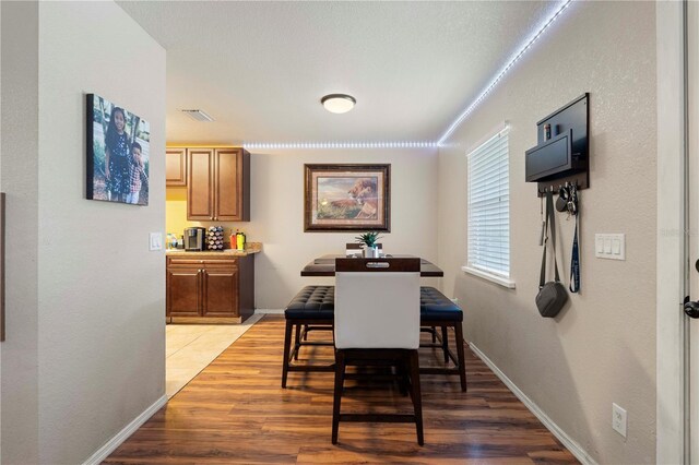 dining space with baseboards, light wood finished floors, and visible vents