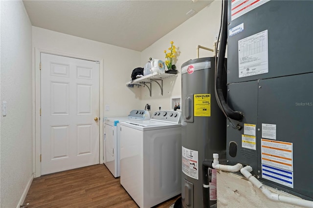 laundry area with heating unit, wood finished floors, washer and clothes dryer, water heater, and laundry area