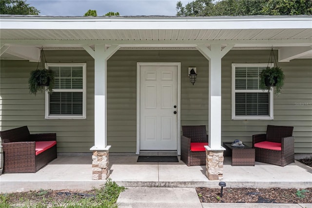 entrance to property featuring covered porch and an outdoor hangout area