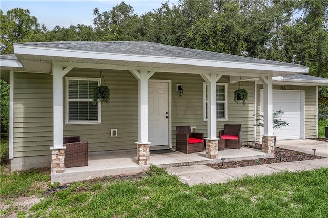 single story home with a shingled roof, an attached garage, a porch, and driveway