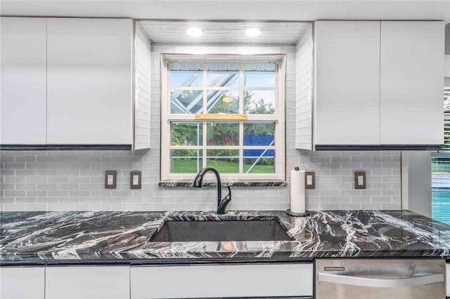 kitchen featuring decorative backsplash, sink, white cabinetry, and dark stone countertops