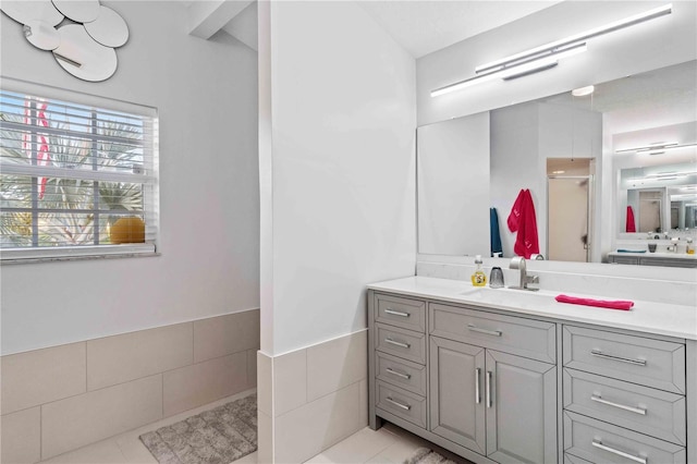 bathroom with walk in shower, vanity, tile walls, and tile patterned floors