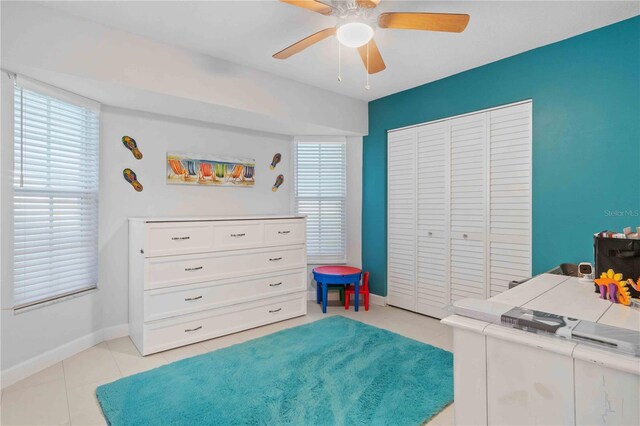 tiled bedroom featuring ceiling fan and a closet