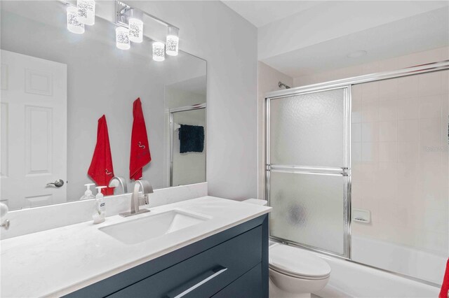 full bathroom with toilet, vanity, and shower / bath combination with glass door