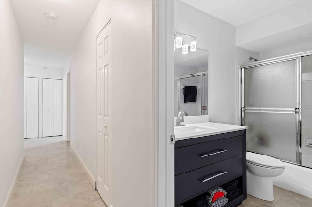 full bathroom featuring combined bath / shower with glass door, vanity, and toilet