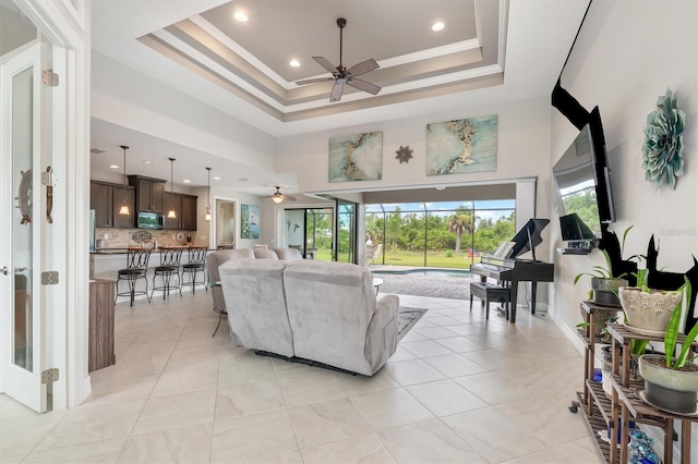 living room with crown molding, ceiling fan, and a tray ceiling